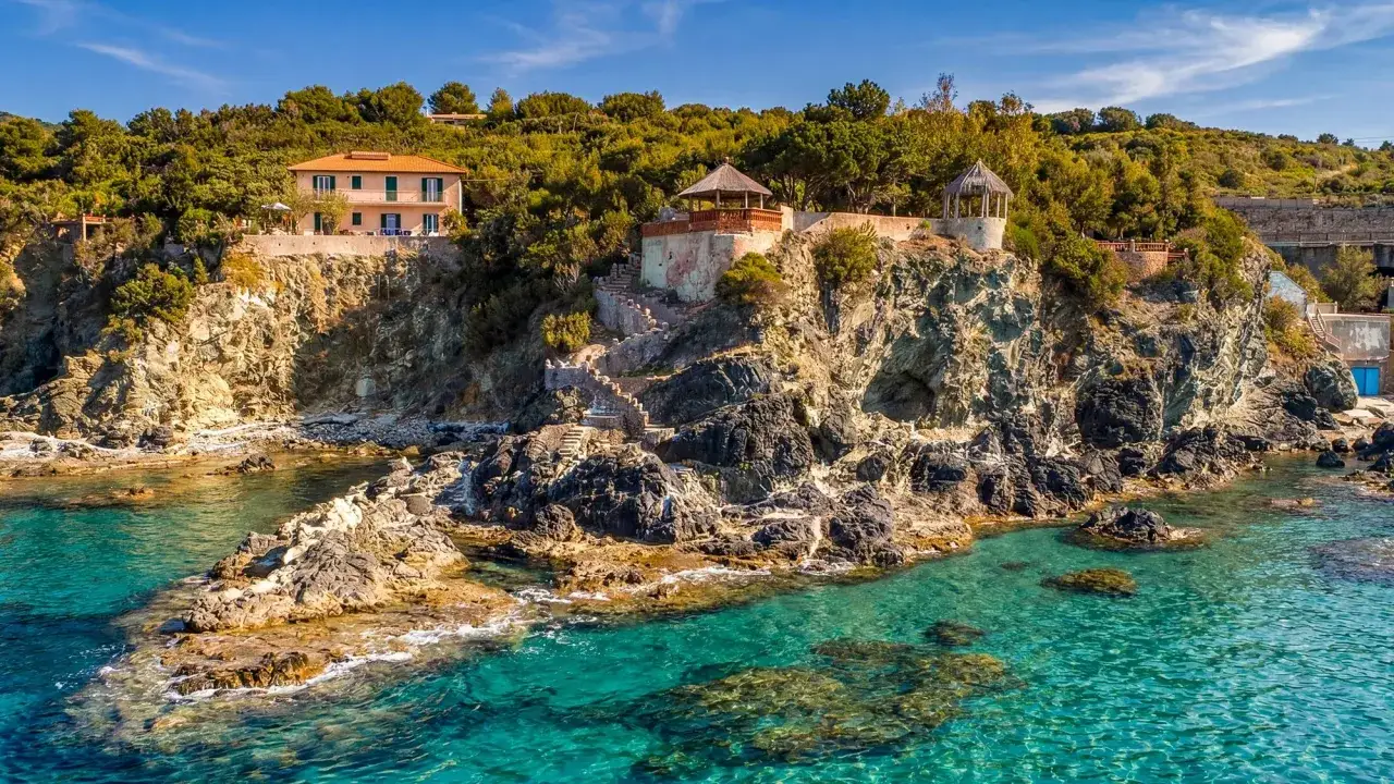 Villa Mazzanta, perch&eacute;e sur une falaise rocheuse, surplombe une mer turquoise. Des escaliers m&egrave;nent &agrave; des kiosques ombrag&eacute;s.