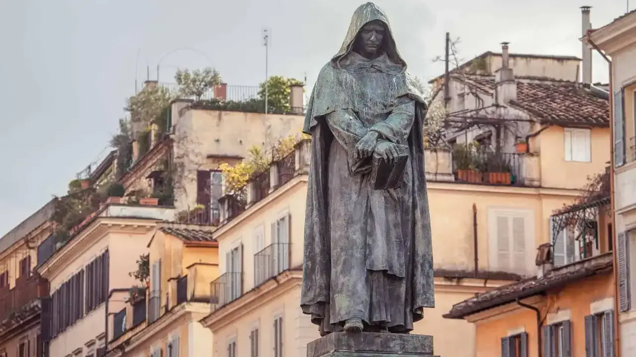 Statue d'un moine tenant un livre, sur fond de bâtiments colorés et de terrasses fleuries à Campo de' Fiori.