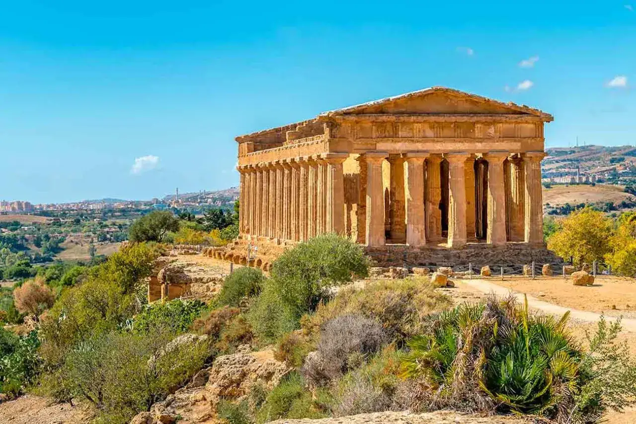 Temple dorique majestueux dans la vallée des temples, sous un ciel bleu éclatant. Paysage méditerranéen verdoyant.