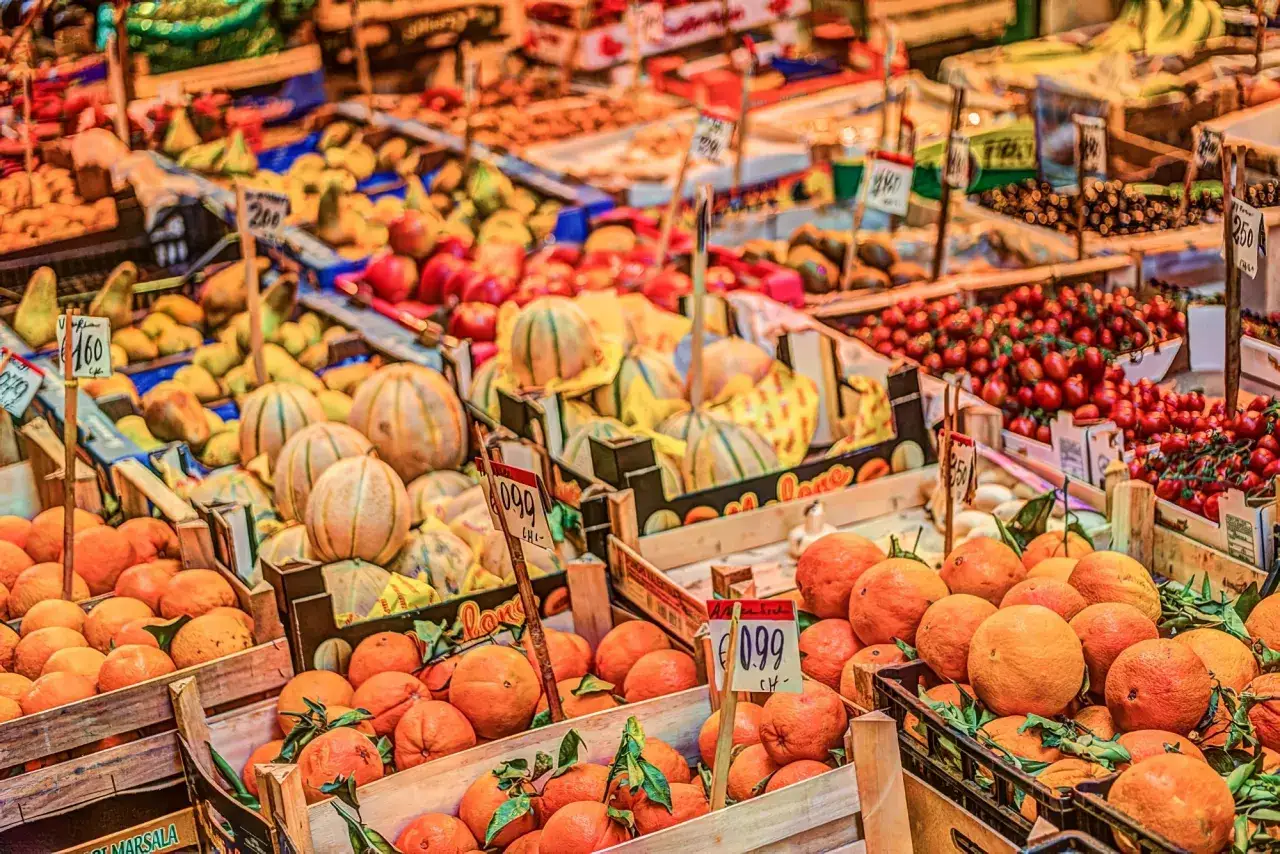 Un joyeux jour de marché en Sicile, avec des étals débordant d'oranges, de melons et de tomates.