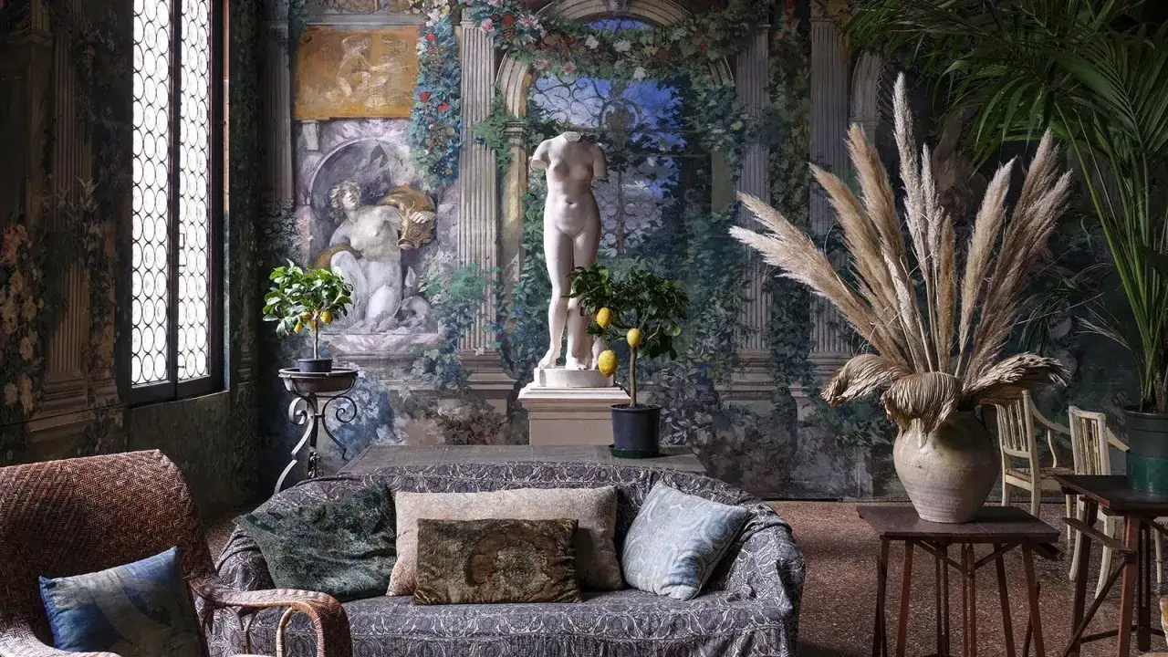 Salon du museo Fortuny, avec une statue antique, un citronnier et des peintures murales luxuriantes.