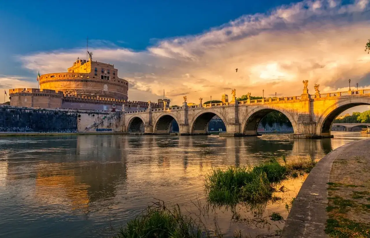 Le majestueux château Saint-Ange à Rome, baigné par la lumière dorée du coucher de soleil, se reflète sur le Tibre.