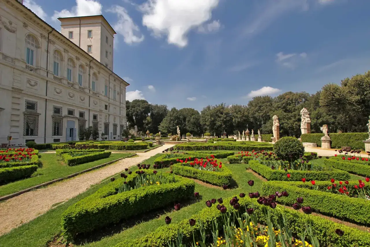Jardin à la française avec tulipes rouges et noires, statues et la Villa Borghese en arrière-plan. Une belle journée pour une visite Villa Borghese.