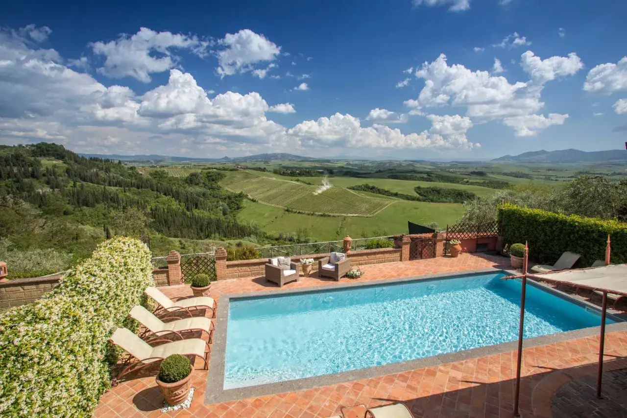 Piscine et chaises longues offrant une vue panoramique sur les collines toscanes. Parfait pour des gîtes en Toscane.