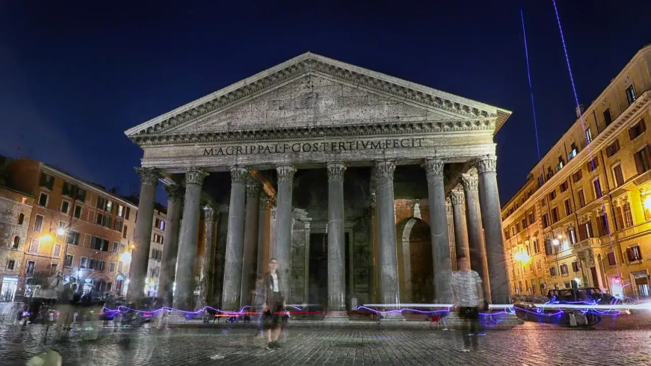 Visite nocturne du Panthéon à Rome, un monument emblématique illuminé, avec des silhouettes fantomatiques de passants et des traînées lumineuses de véhicules.