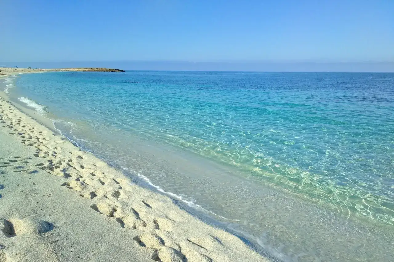 Plage de sable fin, eaux turquoise limpides, parfait pour des vacances en Italie en famille au bord de la mer.