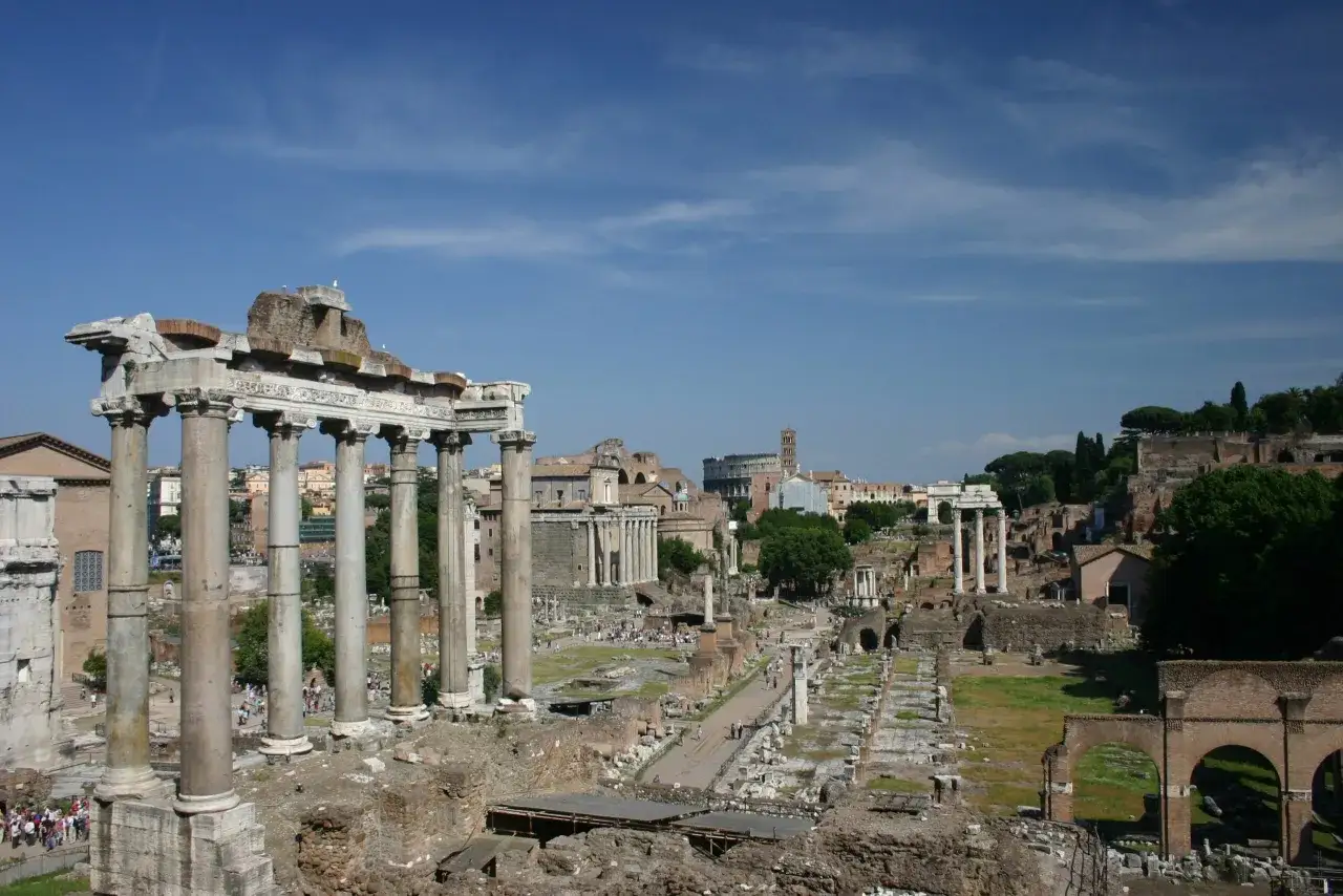 Ruines antiques sur le mont Palatin à Rome, avec des colonnes imposantes et des vestiges de temples sous un ciel bleu.
