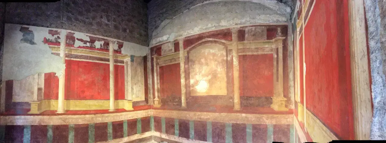 Fresques murales colorées dans une pièce, évoquant l'intérieur d'une maison d'Auguste à Rome. Les motifs architecturaux et les couleurs vives rappellent l'art romain antique.