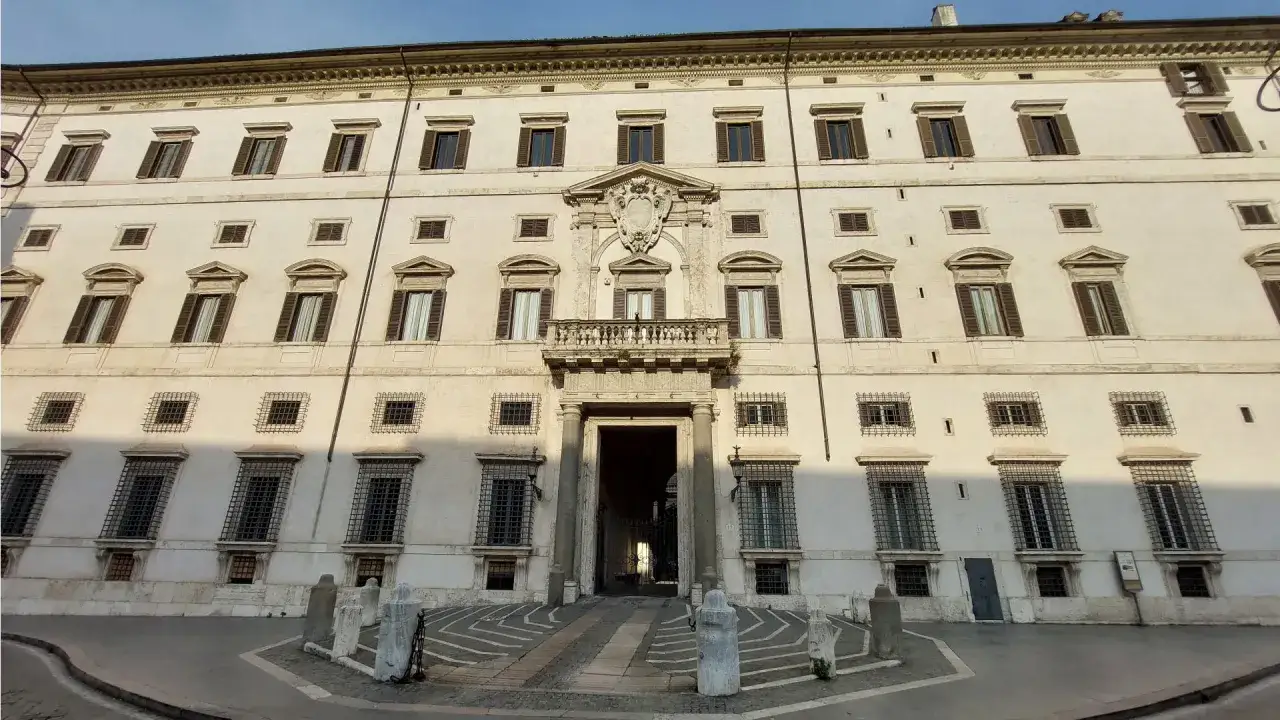 Façade imposante du Palais Borghese à Rome, avec ses fenêtres symétriques, son balcon orné et son entrée voûtée.
