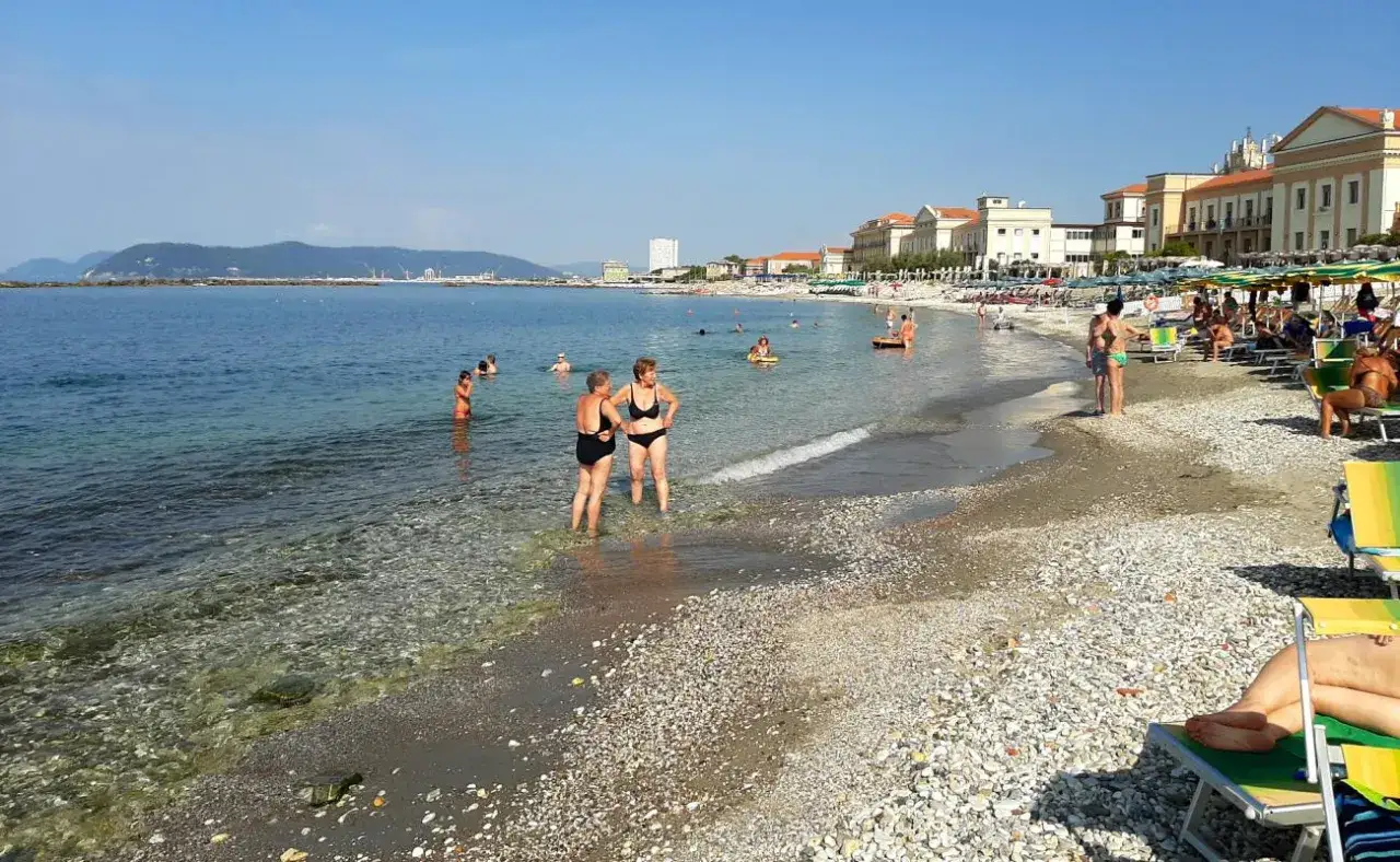 Plage de Massa, Italie. Des baigneurs profitent de l'eau claire et du soleil sur cette plage de galets.