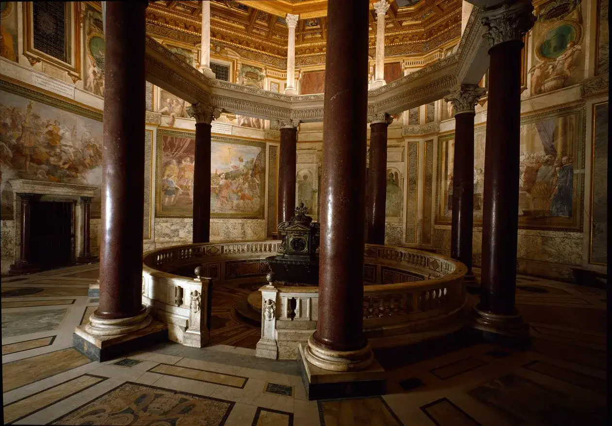 Int&eacute;rieur d'une chapelle de la cath&eacute;drale de Rome, avec des colonnes de marbre rouge, des fresques murales et un autel circulaire.