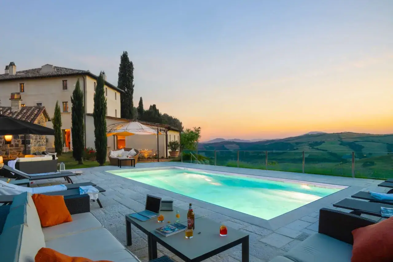 Magnifique villa en location en Italie, avec piscine illuminée et vue panoramique sur les collines toscanes au coucher du soleil. Parfait pour des vacances de rêve.