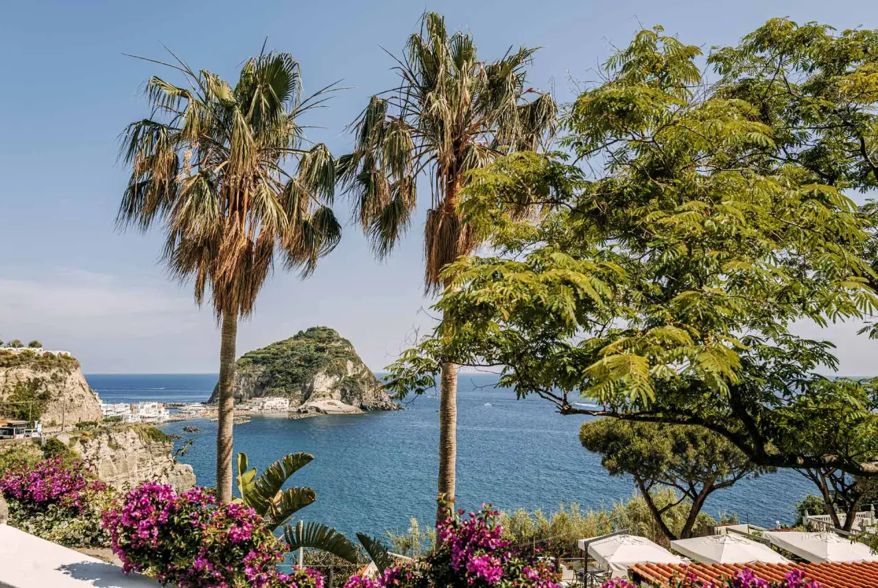 Vue panoramique de Sant'Angelo, Ischia, avec palmiers, bougainvilliers et la mer bleue.