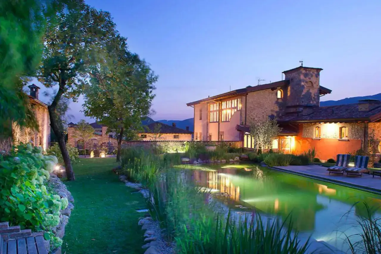 Un paisible agriturismo en Italie du Nord, avec une piscine illumin&eacute;e et des b&acirc;timents en pierre.