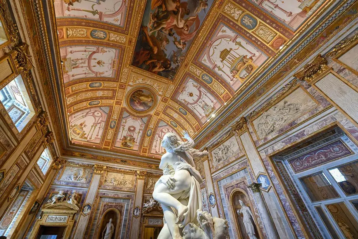 Magnifique sculpture au centre d'une salle ornée de fresques dorées. La sculpture Villa Borghese semble figée dans un mouvement dramatique, contrastant avec la richesse du décor.