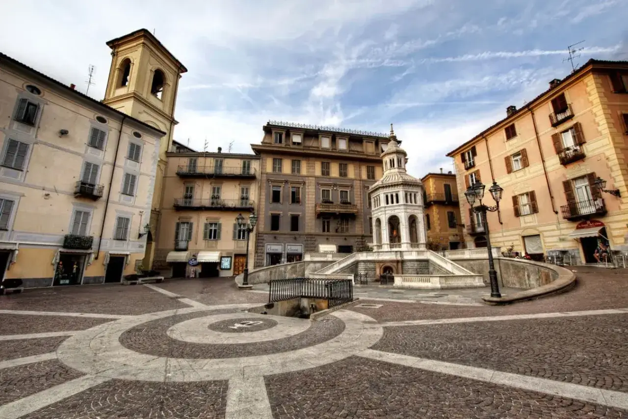 Place publique avec fontaine centrale, entour&eacute;e de b&acirc;timents color&eacute;s. Un endroit id&eacute;al pour acqui terme et se d&eacute;tendre.