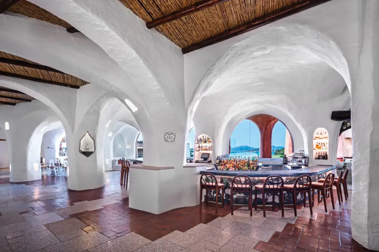 Bar lumineux avec vo&ucirc;tes blanches et vue sur la mer, typique du style du Hotel Su Gologone.