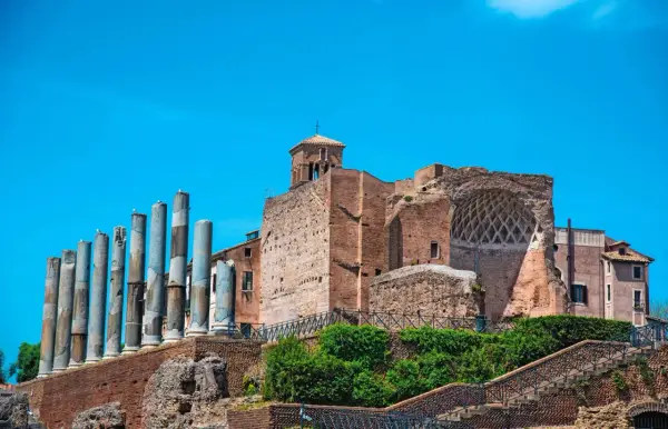 Vestiges de la Domus Aurea, avec ses colonnes antiques et ses ruines de briques sous un ciel bleu éclatant.