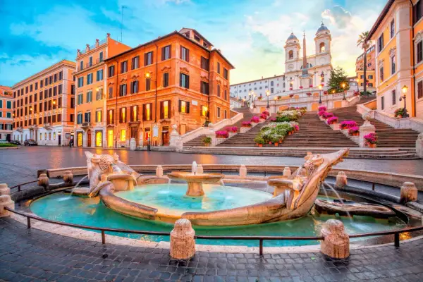 Fontaine de la Barcaccia et l'escalier d'Espagne à Rome au lever du soleil, avec des fleurs colorées.